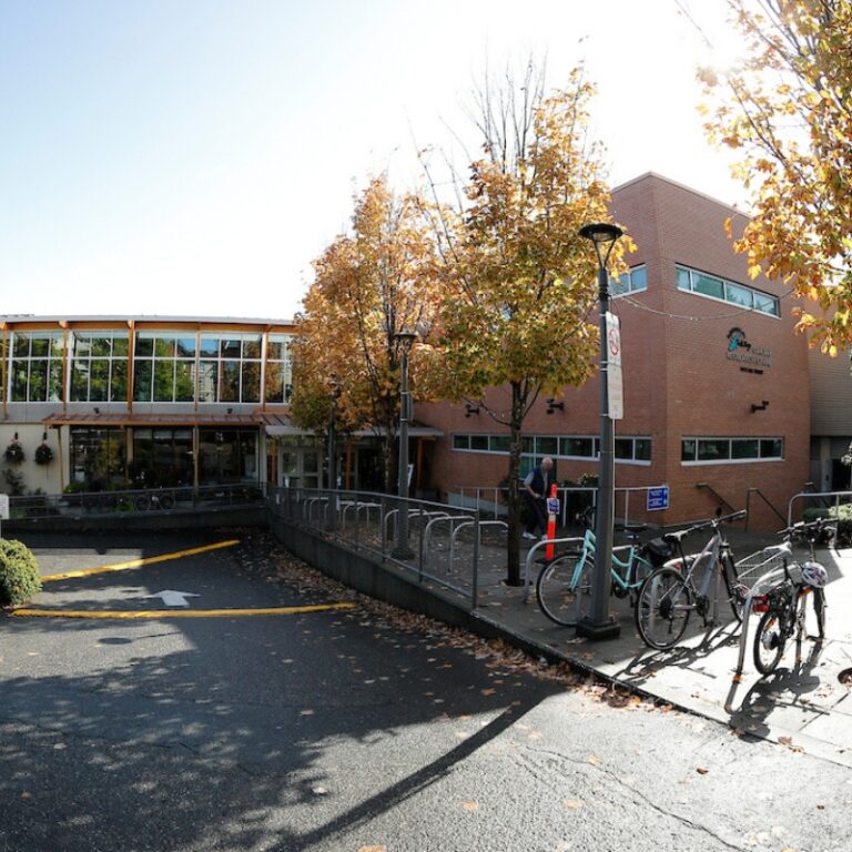 Outside shot of Oak Bay Recreation Centre on Bee Street. Bikes parked in bike racks on a blue sky day.