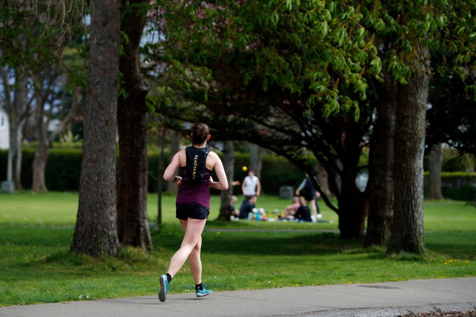 A woman in running athletic gear runs along a sidewalk in Oak Bay.
