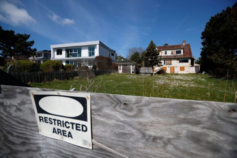 A house in the background features boarded up windows, with fencing closing it off for construction and a sign that reads "restricted area"